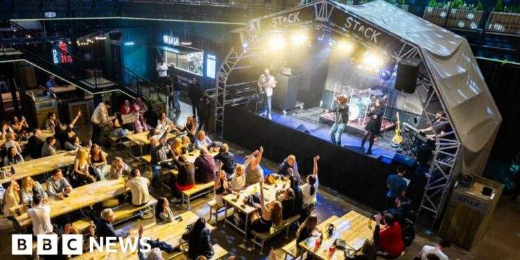 People sitting at tables watching a band perform on stage at Stack Lincoln